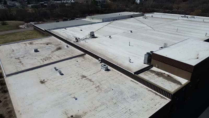 Aerial view of a building with multiple roof sections and membrane types